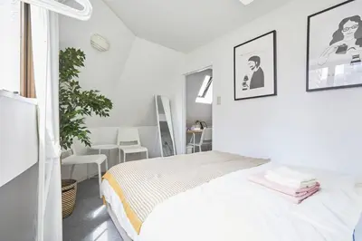 a white bedroom with a bed and a table and chairs at TORA HOTEL Tokyo-kitaueno \u5bc5\u30db\u30c6\u30eb\u5317\u4e0a\u91ce in Tokyo