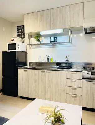 a kitchen with wooden cabinets and a black refrigerator at Alo BnB 6 - Near IKEBUKURO, SHINJUKU, UENO, AKIHABARA - Self check-in in Tokyo