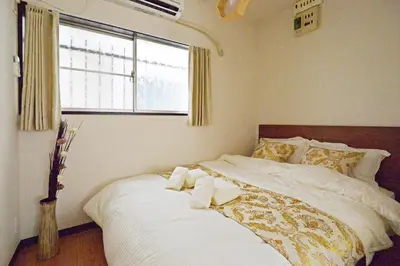 a bedroom with a large white bed with a window at YUZU HOUSE in Tokyo