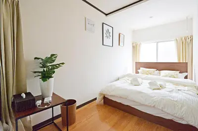 a white bedroom with a bed and a window at YUZU HOUSE in Tokyo