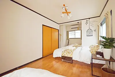 a bedroom with two beds and a table and a window at YUZU HOUSE in Tokyo