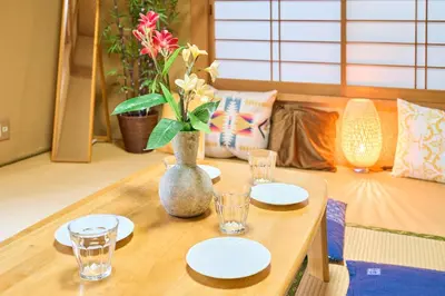 a table with plates and a vase with flowers on it at Comfy Home Koiwa in Tokyo