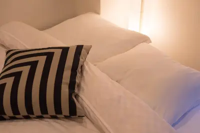 a bed with white sheets and a black and white pillow at TORA HOTEL Tokyo Skytree \u5bc5\u30db\u30c6\u30eb \u30b9\u30ab\u30a4\u30c4\u30ea\u30fcD in Tokyo