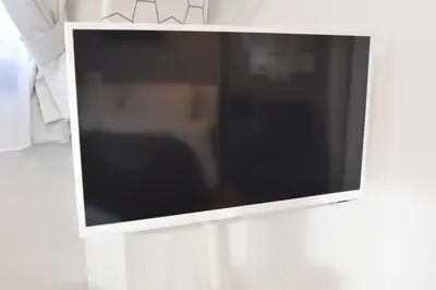 a flat screen tv hanging on a white wall at Tune Inn Ebisu in Tokyo