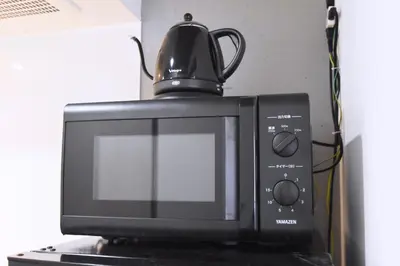 a black microwave with a tea kettle on top of it at Tune Inn Ebisu in Tokyo