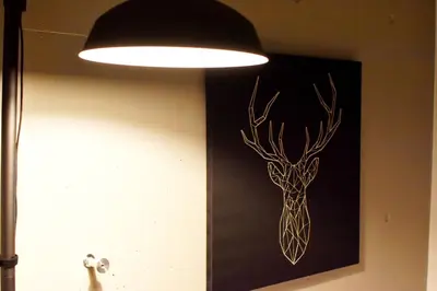 a light hanging on a wall with a picture of a deer at Tune Inn Ebisu in Tokyo
