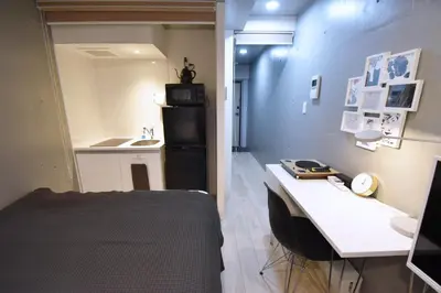 a room with a bed and a desk and a kitchen at Tune Inn Ebisu in Tokyo