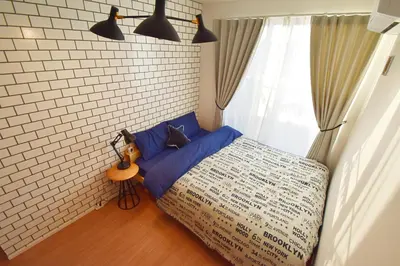 a bedroom with a bed with blue pillows and a window at FINOA Residential Suite Asakusa/Oshiage Skytree in Tokyo