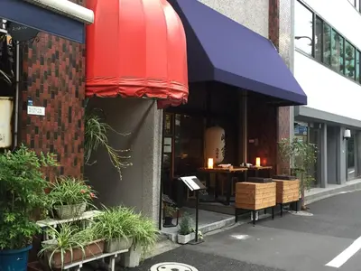 a restaurant with a red awning and tables and plants at Tokyo Kakan in Tokyo