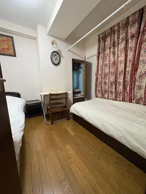 a room with two beds and a table and a clock at Tokyo Kakan in Tokyo