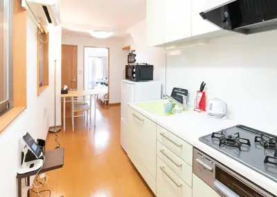 a kitchen with white cabinets and a stove top oven at Yahiro 4-chome House 1F in Tokyo
