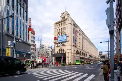 a busy city street with a tall building with a crosswalk at Yahiro 4-chome House 1F in Tokyo