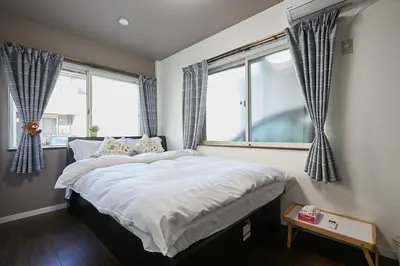 a bedroom with a large bed and two windows at Ka's house in Tokyo