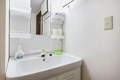 a white bathroom with a sink and a mirror at Ka's house in Tokyo