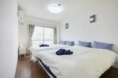 two beds in a white room with blue pillows on them at Sun white Gyoutoku 303 in Tokyo