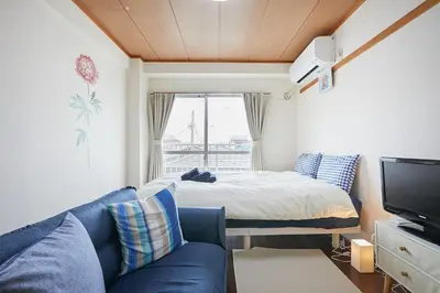 a living room with a blue couch and a bed at Sun white Gyoutoku 303 in Tokyo