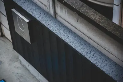 a black door with a sign on the side of a building at bmj Hyakunincho in Tokyo