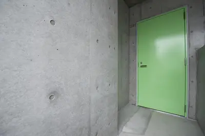 a green door in a room with a wall at bmj Hyakunincho in Tokyo