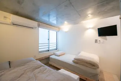 a small room with two beds and a window at bmj Hyakunincho in Tokyo
