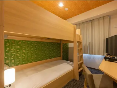 a bedroom with bunk beds and a desk with a television at Tosei Hotel Cocone Asakusa Kuramae in Tokyo
