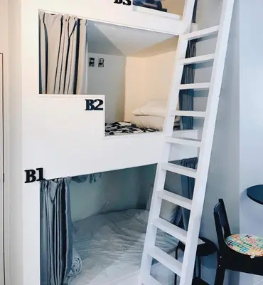 a bunk bed in a small room with a ladder at Hostel 1010 TOKYO in Tokyo