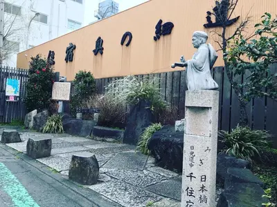 a statue of a man on aolith in front of a building at Hostel 1010 TOKYO in Tokyo