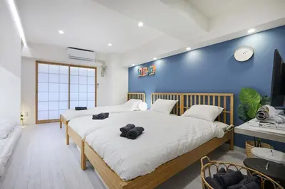 a bedroom with two beds and a blue wall at STAY ARI Kabukicho in Tokyo