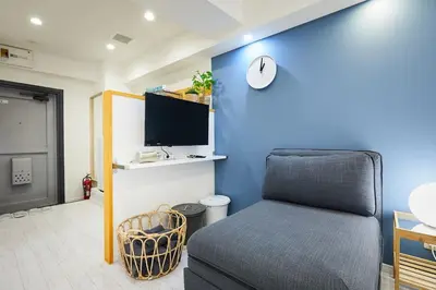 a room with a bed and a tv on a blue wall at STAY ARI Kabukicho in Tokyo
