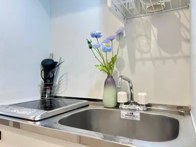 a kitchen sink with a vase with flowers in it at nestay inn tokyo kagurazaka in Tokyo