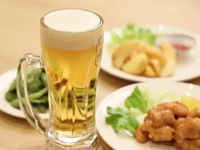 a glass of beer sitting on a table with plates of food at Smart Stay SHIZUKU Ueno Ekimae in Tokyo
