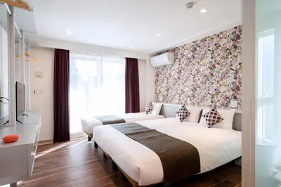 two beds in a hotel room with a floral wallpaper at Hotel SAILS Asakusa in Tokyo