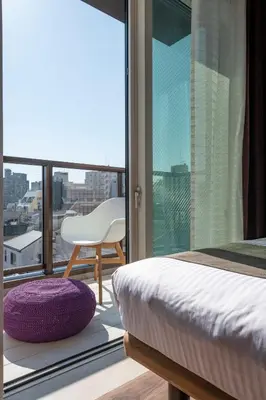 a bedroom with a bed and a chair and a window at Hotel SAILS Asakusa in Tokyo