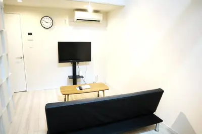 a living room with a couch and a tv on a wall at Shibuya Stay Tokyo B103 in Tokyo