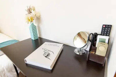 a table with a book and a mirror and a lamp at nestay suite tokyo tabata in Tokyo