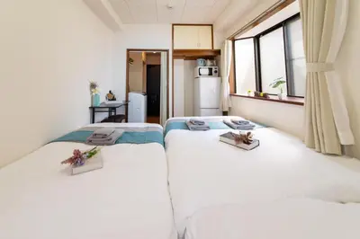 two twin beds in a room with a window at nestay suite tokyo tabata in Tokyo