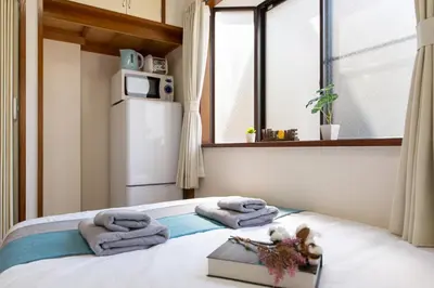 a bedroom with a bed with towels and a window at nestay suite tokyo tabata in Tokyo