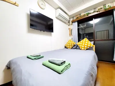 a bedroom with a white bed with a flat screen tv at nestay suite tokyo tabata in Tokyo