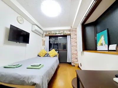 a small room with two beds and a television at nestay suite tokyo tabata in Tokyo