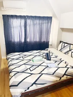 a bed with a black and white comforter and a window at \u6d45\u8349\u57084\u5c42\u72ec\u680b\u522b\u5885 \u514d\u8d39\u505c\u8f66\u573a \u8fd1\u8f66\u7ad9 \u53ef\u76f4\u8fbe\u673a\u573a in Tokyo
