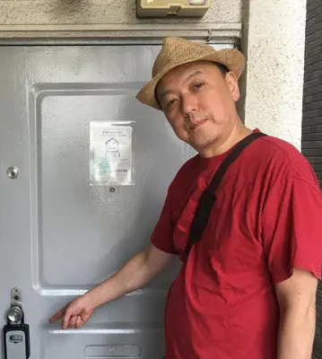 a man wearing a hat standing in front of a refrigerator at G&R House 201 in Tokyo