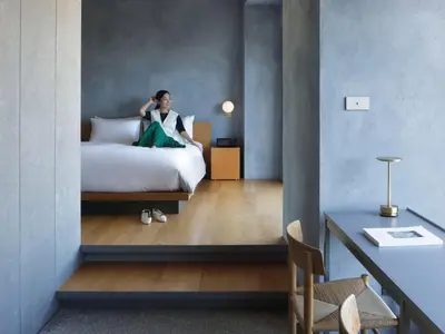a woman sitting on a bed in a hotel room at sequence MIYASHITA PARK - Shibuya in Tokyo