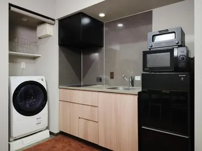 a kitchen with a washing machine and a microwave at MONday Apart Premium Nihonbashi in Tokyo