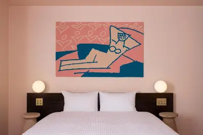 a bedroom with a bed and a painting on the wall at BnA WALL in Tokyo