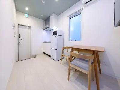 a small white kitchen with a table and a chair at COTO Tokyo Shibuya 8 in Tokyo
