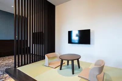 a room with two chairs and a table and a tv at Wires Hotel Shinagawa Seaside in Tokyo