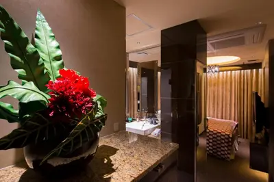 a bathroom with a sink and a vase with red flowers at HOTEL GLANZ CASCATA in Tokyo