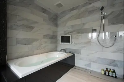 a bathroom with a tub and a tv on a wall at HOTEL GLANZ CASCATA in Tokyo