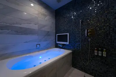 a bathroom with a tub with a tv and a shower at HOTEL GLANZ CASCATA in Tokyo