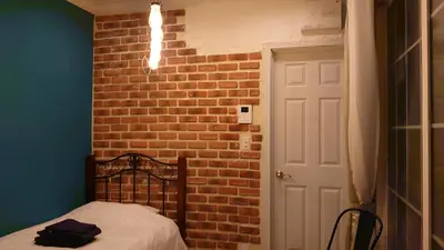 a bedroom with a brick wall and a bed in a room at \u30db\u30c6\u30eb The Standard Apartment SHIBUYA SASAZUKA B\u30eb\u30fc\u30e0 in Tokyo