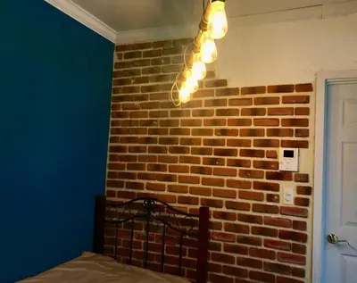 a bedroom with a brick wall and a chandelier at \u30db\u30c6\u30eb The Standard Apartment SHIBUYA SASAZUKA B\u30eb\u30fc\u30e0 in Tokyo